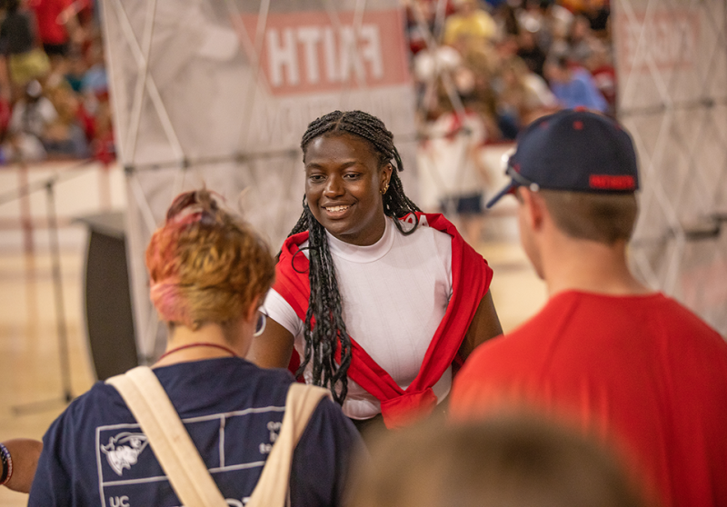 Young woman greeting students at a campus event