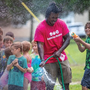 A Cumberlands students plays in a water hose with local children during a summer event. 