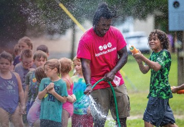 A Cumberlands students plays in a water hose with local children during a summer event. 