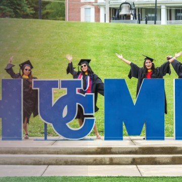 Students celebrate at the Cumberlands HOME sign during graduation. 
