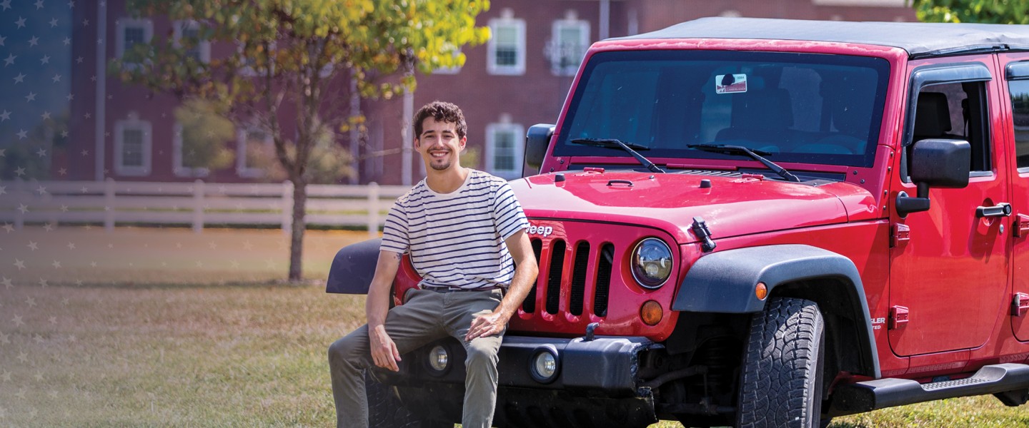 A student poses with his vehicle on campus. 