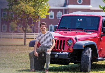 A student poses with his vehicle on campus. 