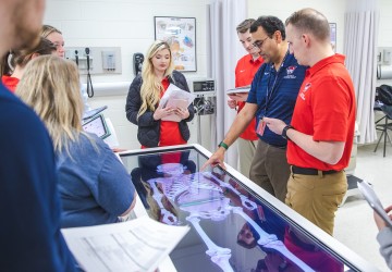 Physical therapy students participate in an anatomy exercise with their professor. 